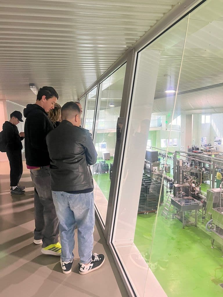 Doi elevi urmăresc utilajele fabricii de lactate prin geamul de vizitare