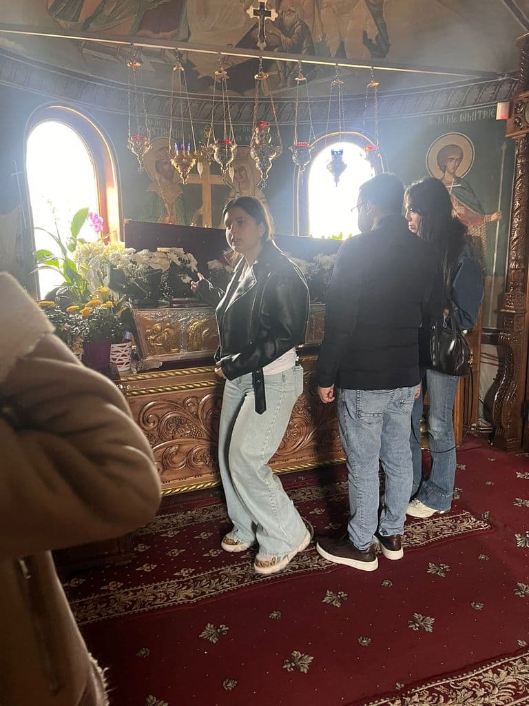 Elevi în interiorul unei biserici, printre icoane și covoare roșii