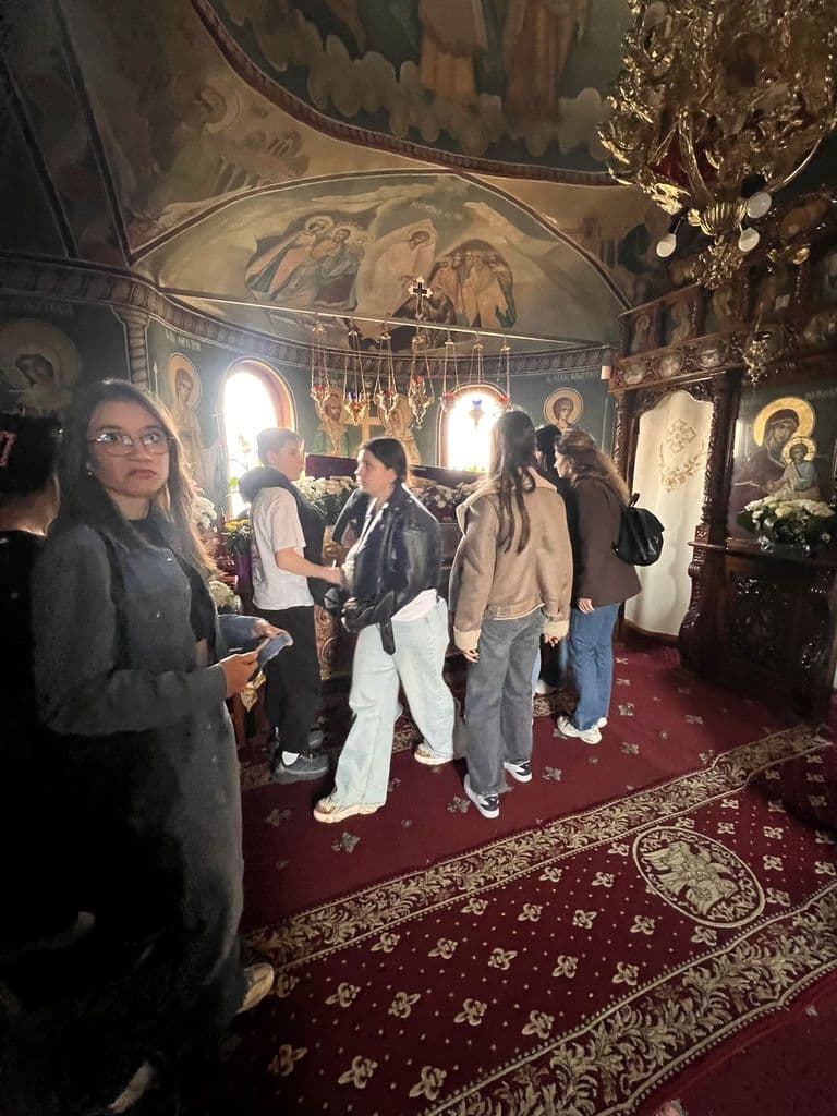 Grupul de elevi ascultă explicații în interiorul unei biserici pictate