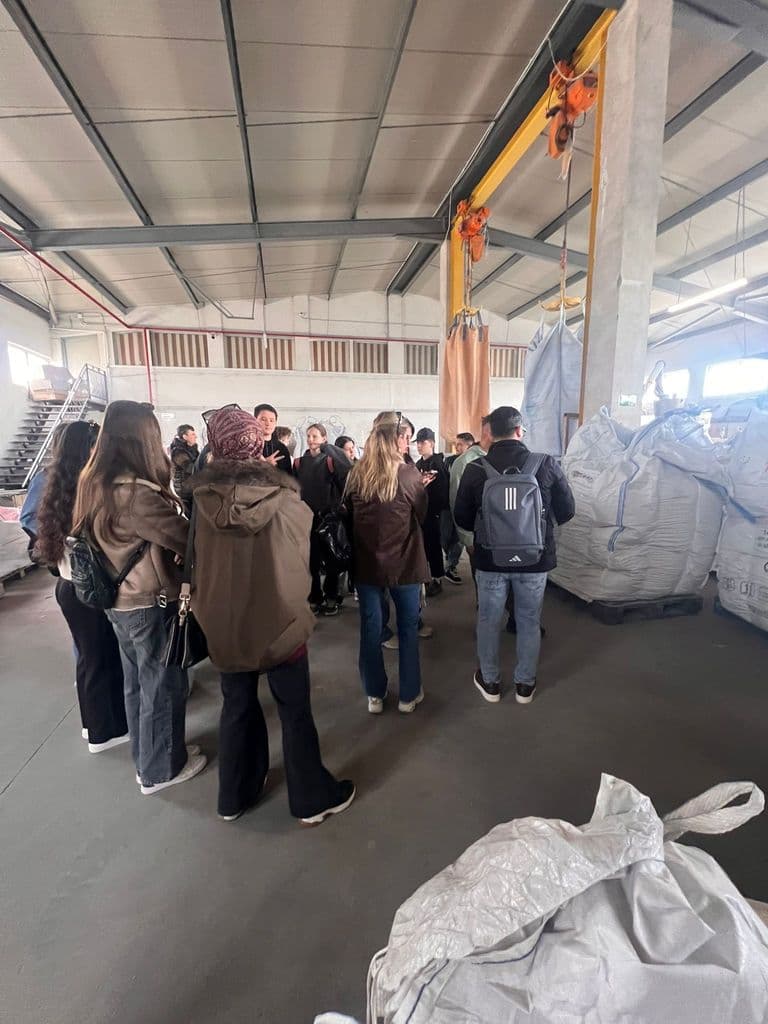 Grupul de elevi ascultă prezentarea, în mijlocul halei de producție
