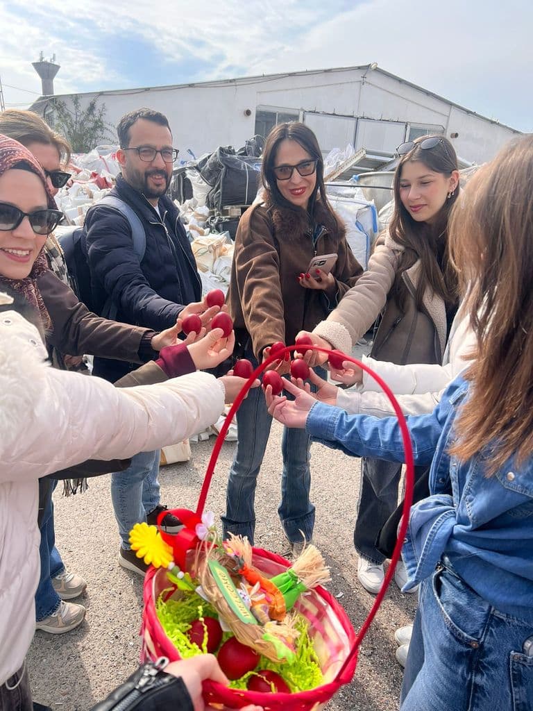 Elevi și profesori ciocnind ouă roșii deasupra unui coș de Paște