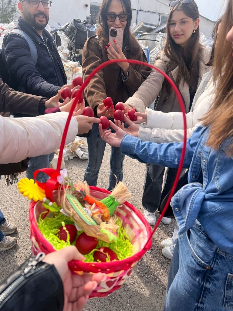 Elevii ciocnesc ouă roșii, adunați în jurul coșului de Paște