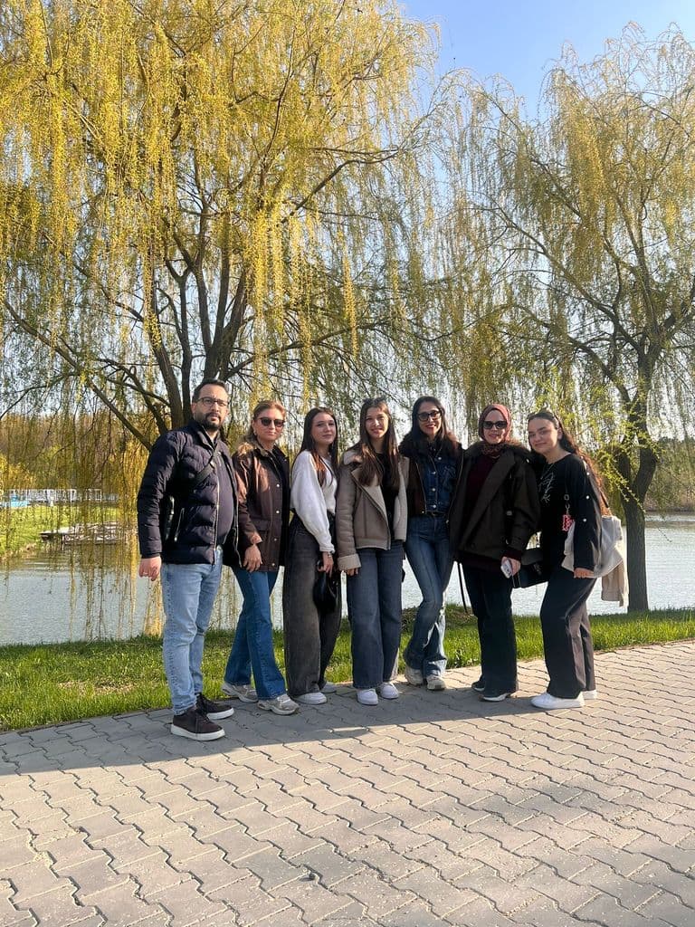 Grup de elevi pe aleea de pe malul apei, între sălcii înverzite